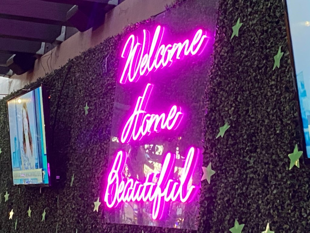 Magenta neon sign reading "Welcome Home Beautiful"